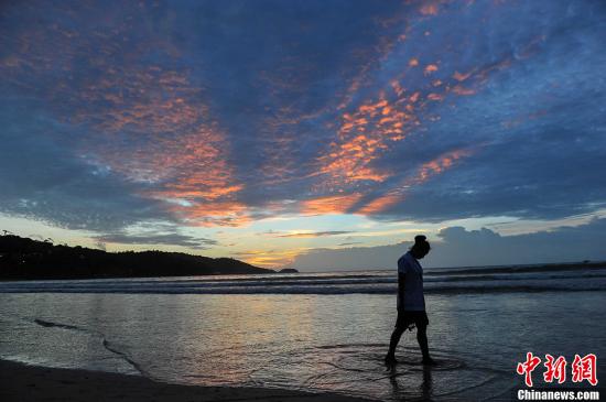 泰國普吉島，圖為一名游客從海灘上走過。洪堅鵬 攝