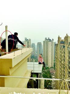圖為胡靜跪在樓頂邊沿苦勸輕生女