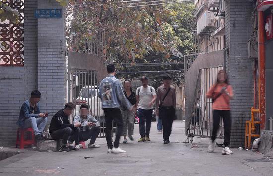 3月16日下午，廣州市白云世界皮具貿易中心旁桂花崗小區。記者連續多日觀察后發現，該小區的幾個入口和內部，長期有拉客人員和望風看場子的人員聚集。 ?? 新京報記者 吳江 攝