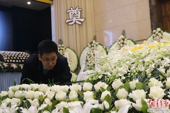 告別儀式開始前，靳中學在整理逝者遺體身旁的鮮花。