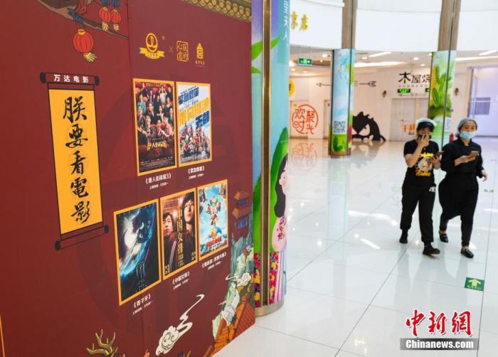 資料圖:2020年5月9日,行人從北京市朝陽區一家尚未恢復營業的電影院的宣傳板前經過。 中新社記者 侯宇 攝